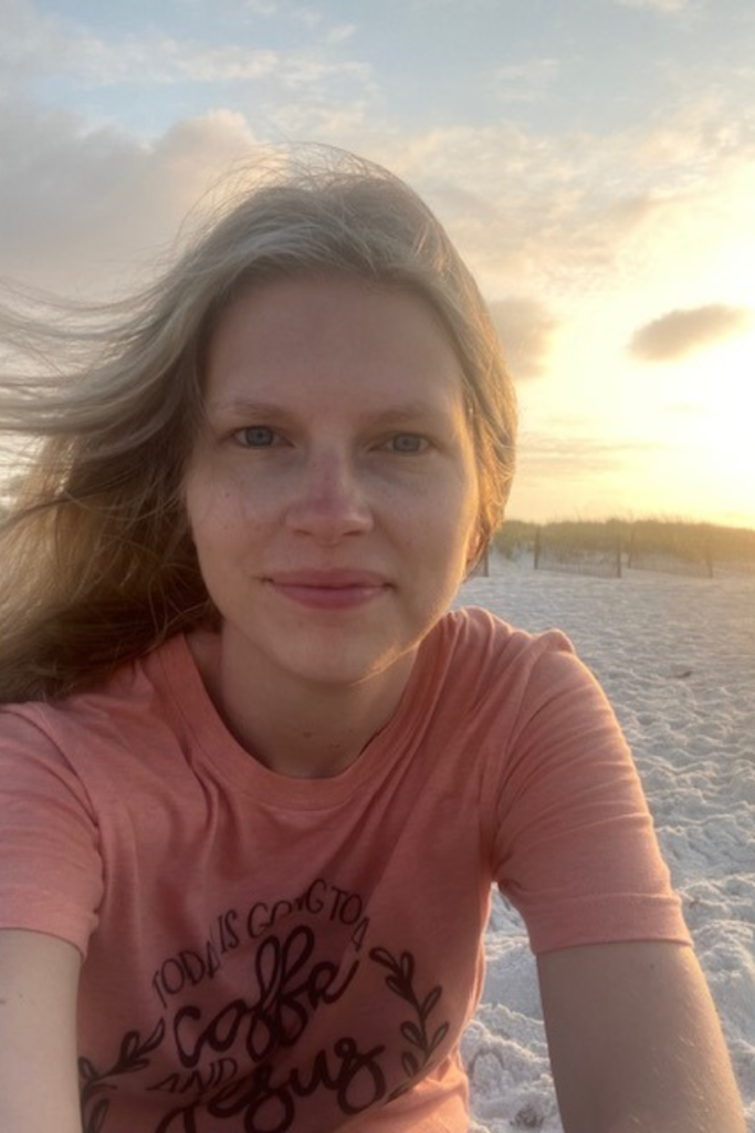 woman sitting on beach as sun rises in background