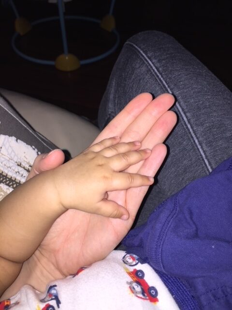 baby's hand rested on top of mom's hand